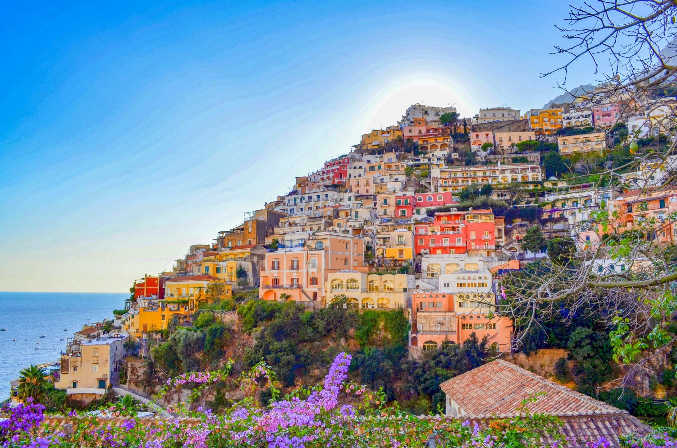 Positano's coral, apricot, and cream houses cascading down the cliff above the blue Mediterranean