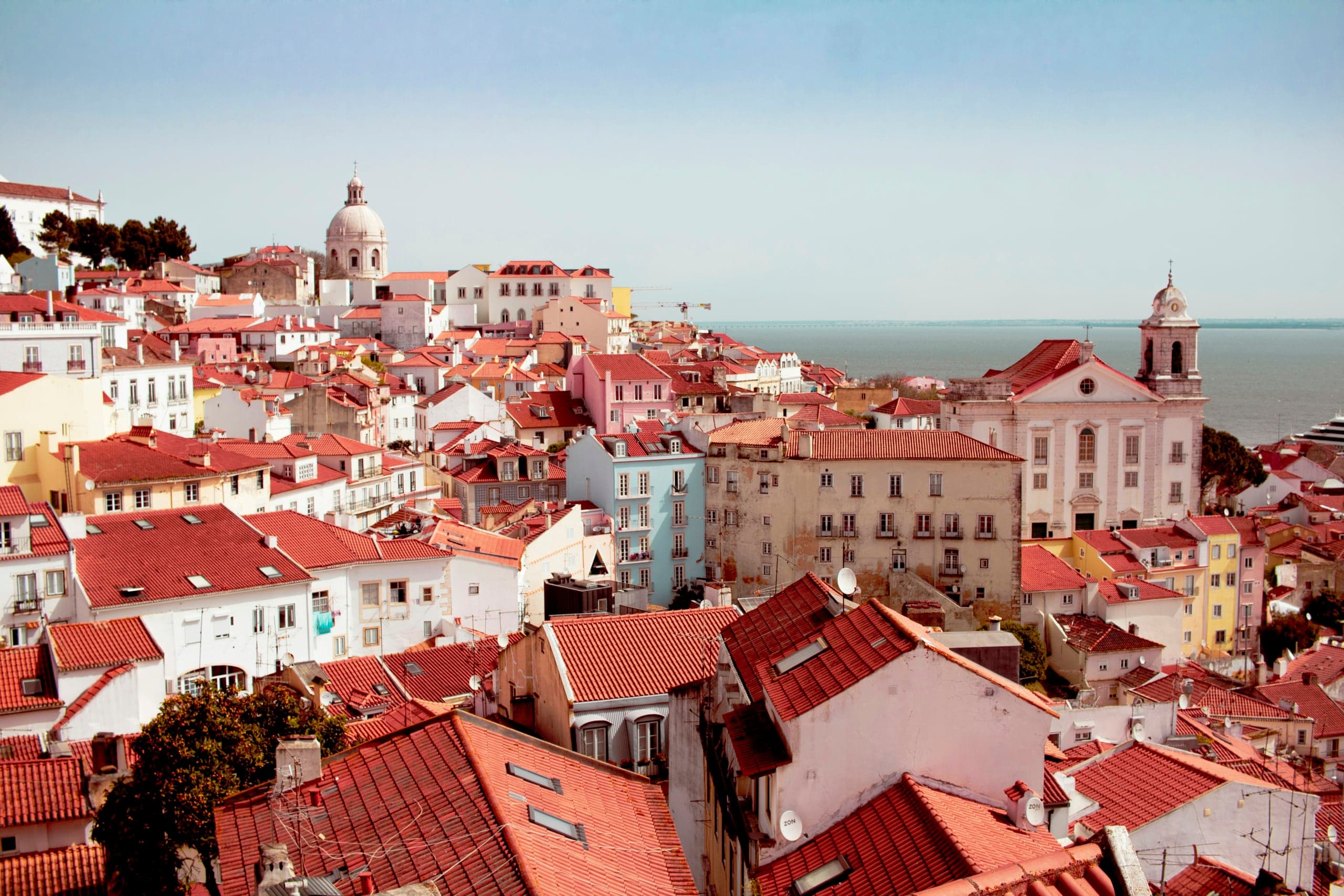 Alfama's red roofs, church towers, and the Tagus from above